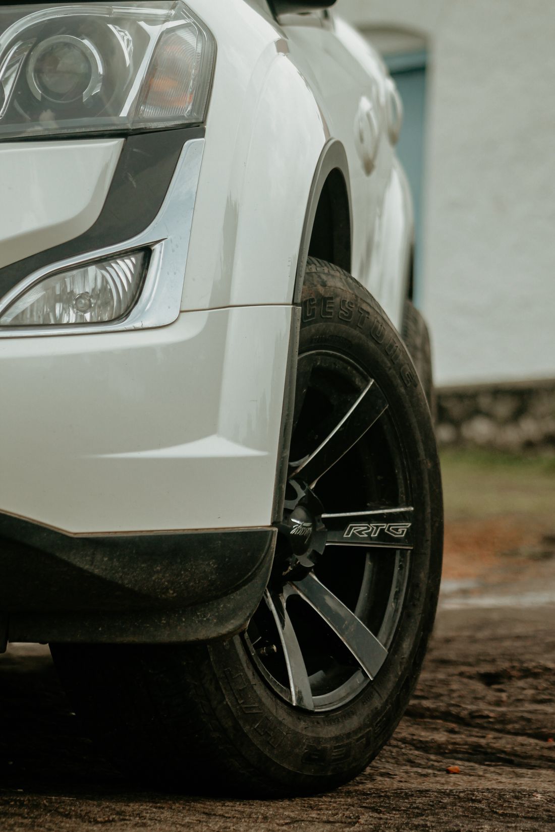 Wheel and sculpted front bodywork of a light-coloured car