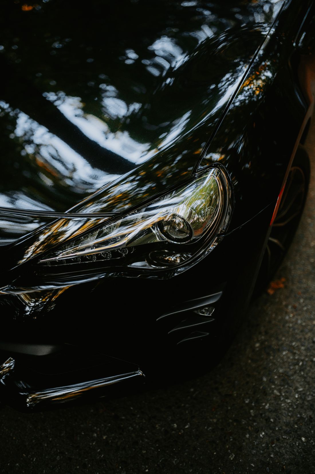 Close-up of a black car headlight and glossy bodywork